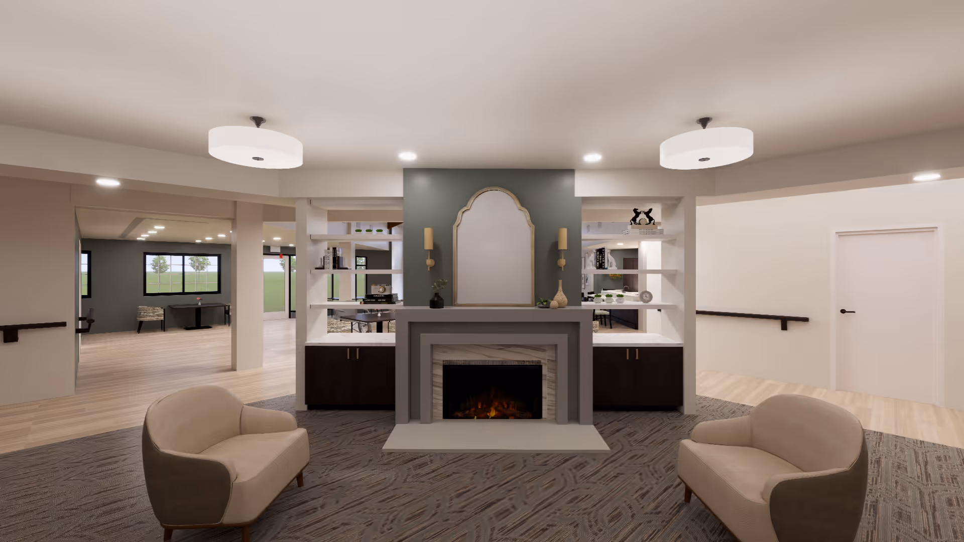 A modern and spacious living area in a senior living facility featuring a central fireplace with a decorative mirror above it, flanked by built-in shelves with decorative items. Two beige armchairs face the fireplace on a patterned carpet. The room has light wood flooring, white walls, and ceiling lights, with open doorways leading to other rooms with large windows.
