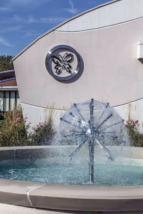 Exterior view of Delmar Gardens on the Green with a circular fountain.