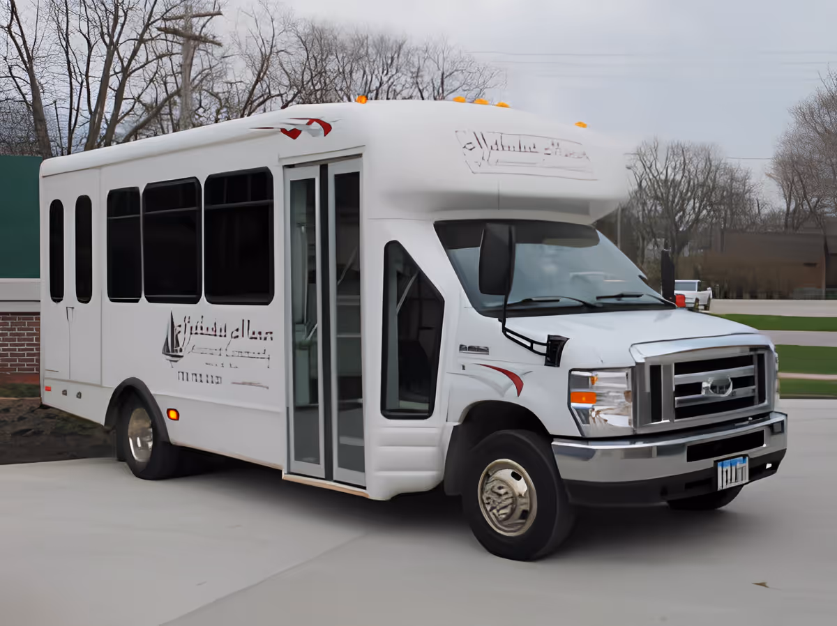 A white Methodist Manor shuttle bus parked outside with its passenger door open.
