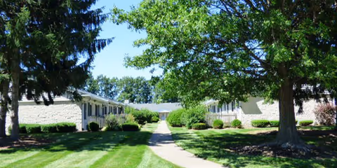 Exterior view of Stow Glen Retirement Village with low buildings, a central path, and green lawns.