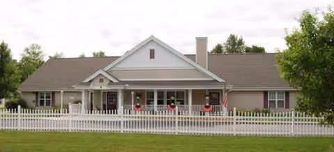 Brookdale Midland senior living facility with a wide porch, white picket fence, and lawn.