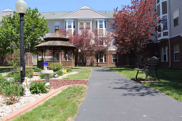 Courtyard of Taeckens Terrace with a gazebo, benches, a paved walkway, and the building facade in the background.