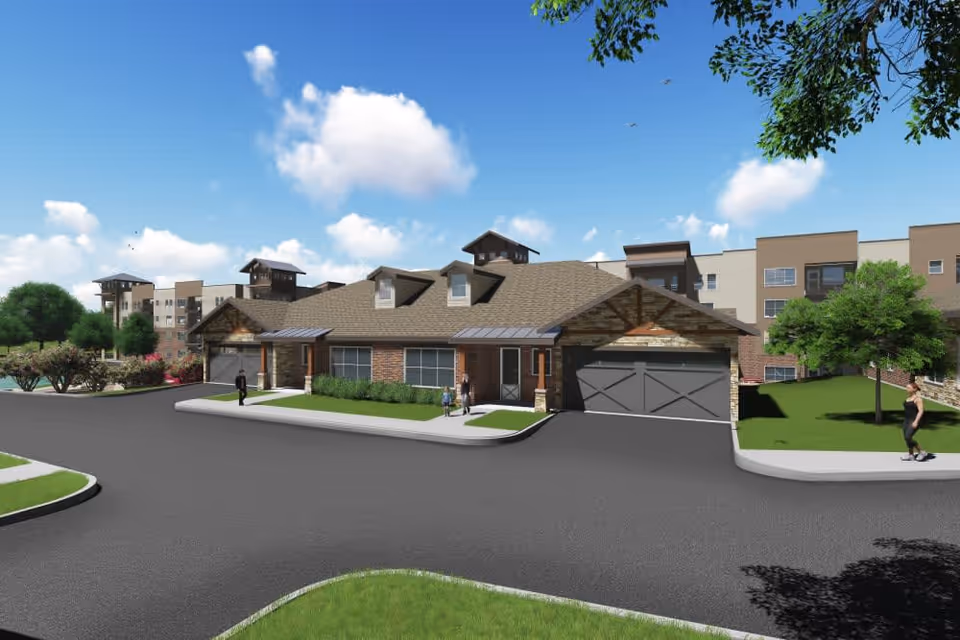 Exterior view of a senior living facility named Watermere at the Preserve, showing a modern building with brick and stone accents, multiple windows, and a garage. The scene includes a paved road, green lawns, trees, and a few people walking outside under a blue sky with some clouds.