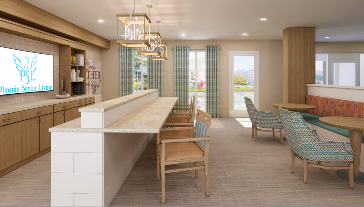 A bright and modern senior living common area featuring a long counter with wooden chairs, a built-in wooden cabinet with a TV displaying the Phoenix Senior Living logo, and a seating area with patterned armchairs and round tables near large windows with green curtains.