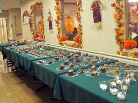Long banquet table with desserts in a fall decorated dining area.