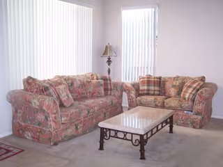 Two floral sofas face a coffee table in a bright living room.