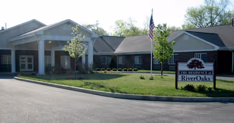 Front exterior view of RiverOaks Health Campus with entrance, flag, and sign.