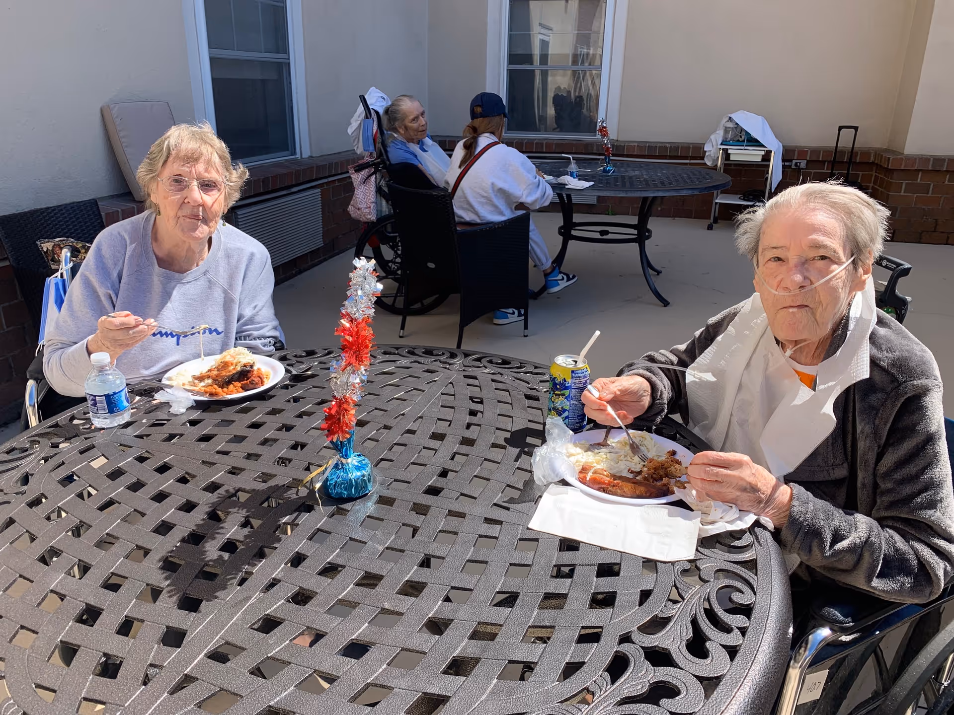 Two senior women enjoying a meal outdoors at a table.
