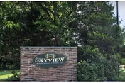 A brick sign for Sky View Rehabilitation & Health Care surrounded by green trees and bushes.