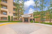 Heritage Villas Senior Apartments exterior: brick building, covered entrance, driveway, and surrounding trees.
