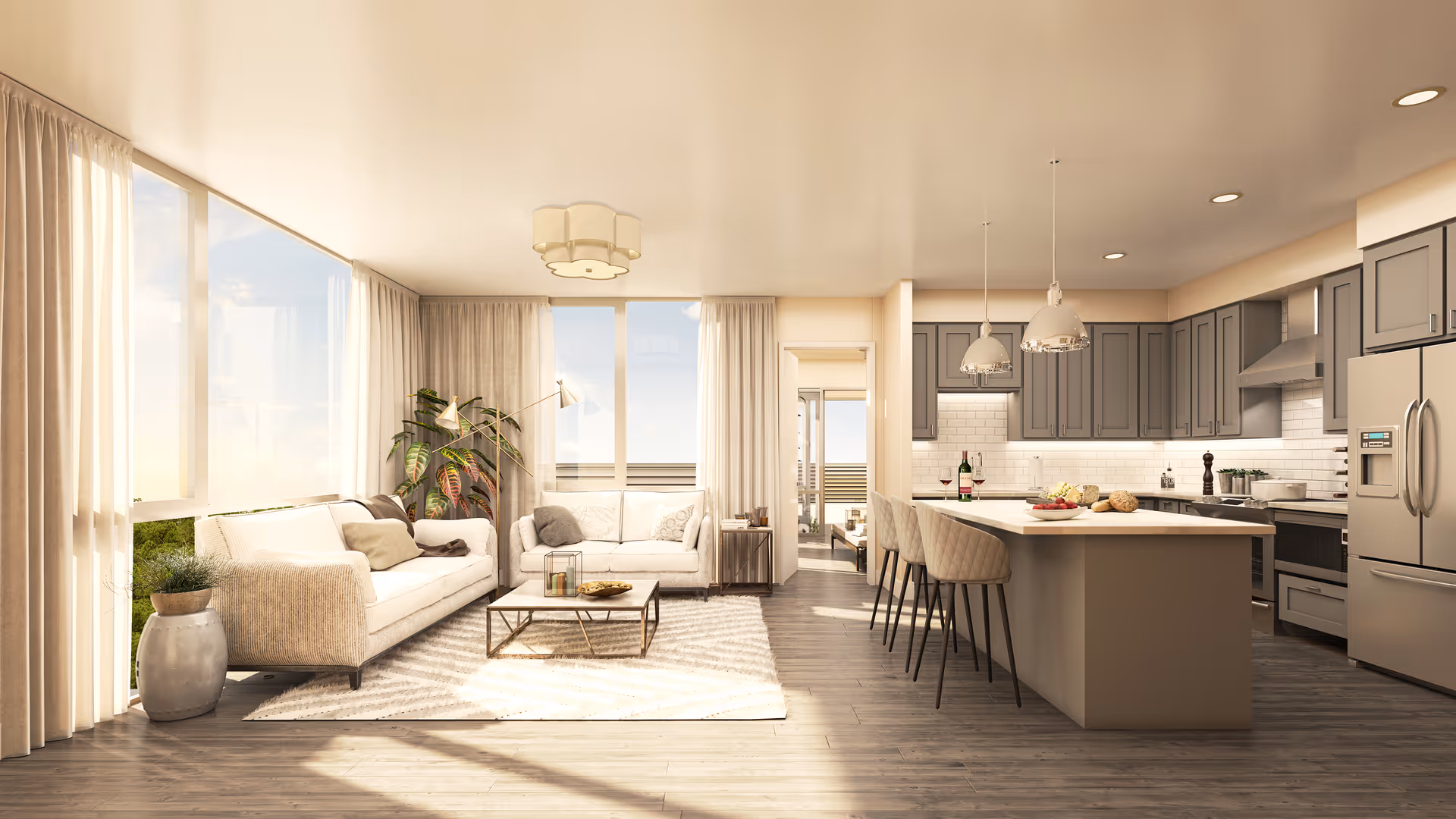 Bright open-plan living area with sofas and a coffee table flowing into a kitchen island with barstools and large windows.