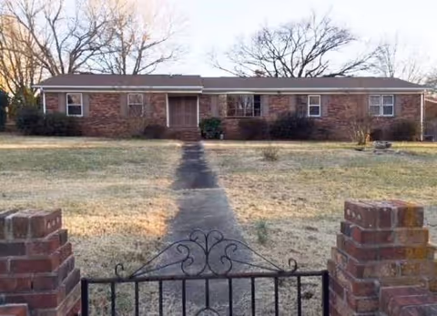 A single-story brick retirement center sits behind a low iron gate and a front walkway.