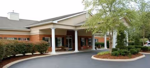 Front entrance of Brookdale Colonial Heights senior living building with brick walls, columns, and curved driveway.