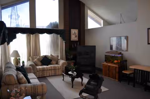 Cozy living room in a senior facility with sofas, coffee table, and TV.