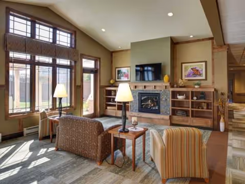 Bright living room with sofas, chairs, lamps, a fireplace, and large windows.