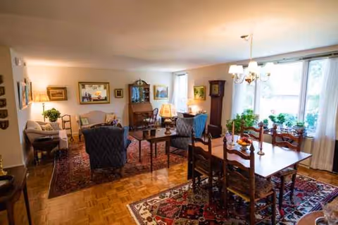 Spacious living and dining area with sofas, tables, rugs, and large windows.