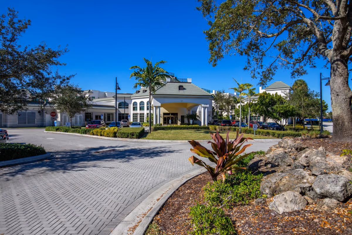 Exterior view of Luxe Senior Living at Wellington entrance with porte-cochère and landscaped driveway.