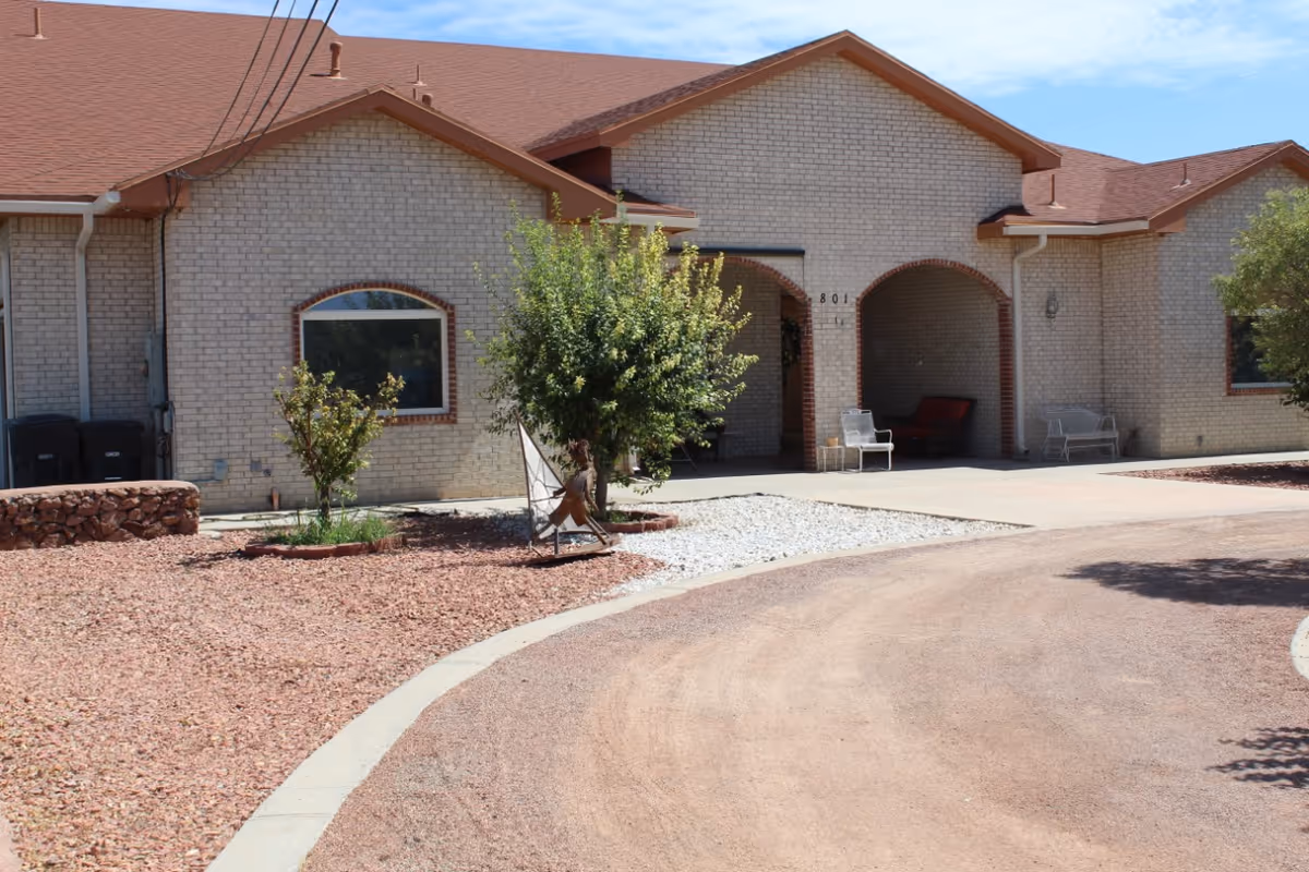Front exterior of a single-story brick building with arched entry, gravel landscaping, and a curved driveway.