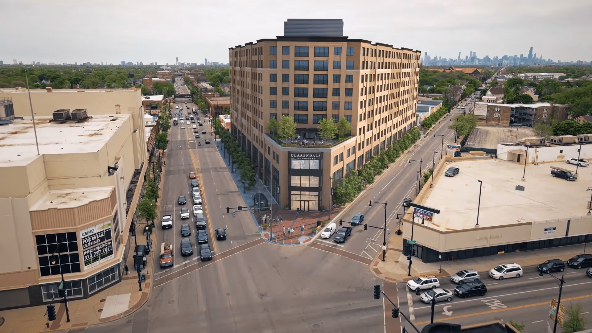 Aerial view of a large multi-story building named Clarendale Six Corners situated at a busy urban intersection with cars on the roads and people walking on the sidewalks. The building has a modern design with large windows and trees lining the sidewalks.