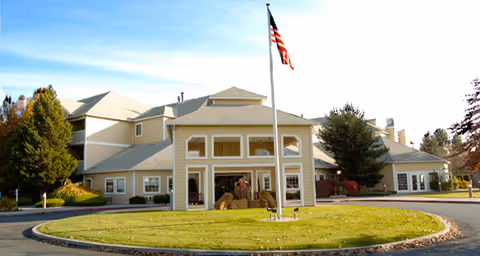 Front exterior of a multi-story senior living building with a flagpole and circular driveway.