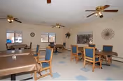 Bright communal dining and activity area with blue-cushioned chairs around tables.