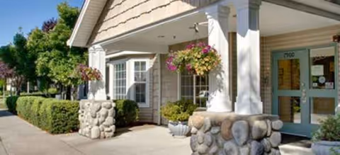 Exterior view of Brookdale Vancouver Stonebridge entrance with columns and hanging baskets.