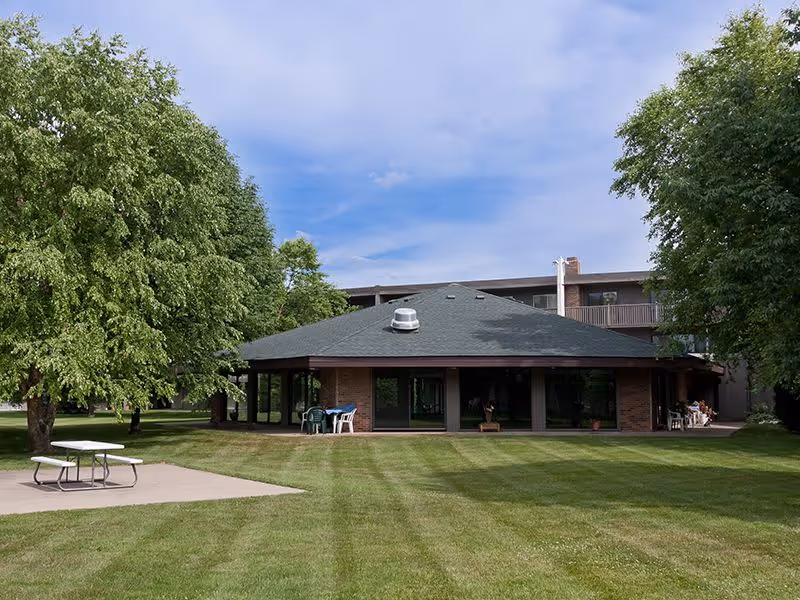 A round building surrounded by greenery and picnic tables at Heathers Estates.