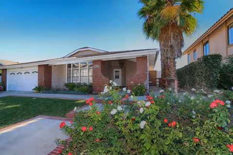 Front view of Verona Court II senior living facility, brick entry, palm tree, and rose bushes.