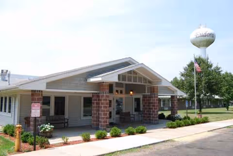 Exterior view of a Medicalodges Eudora facility with a covered entrance and brick pillars.