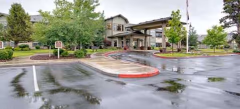 Brookdale Redmond exterior view with entrance, driveway, and wet parking lot under cloudy skies.
