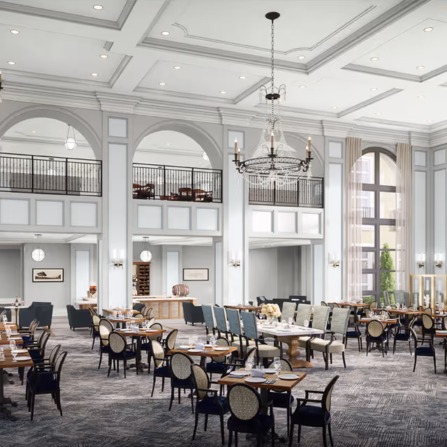 Large elegant dining room with high coffered ceilings, chandeliers, a mezzanine balcony, and multiple tables set for service.