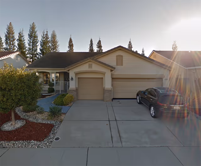 Front view of a beige, single-story home with a two-car garage and driveway.
