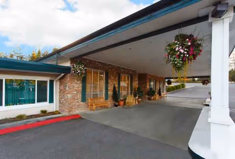 Covered driveway at Life Care Center of Coos Bay with brick exterior and hanging baskets