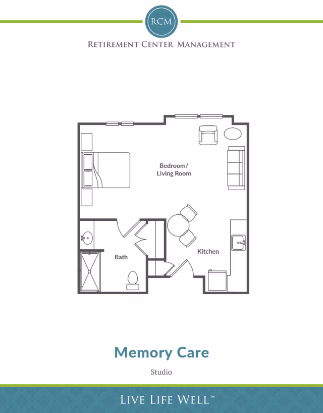 Floor plan of a studio memory care unit showing a combined bedroom and living room area with a bed, chair, sofa, and table. The kitchen area includes a sink, stove, and dining table with two chairs. The bathroom has a shower, toilet, and sink.