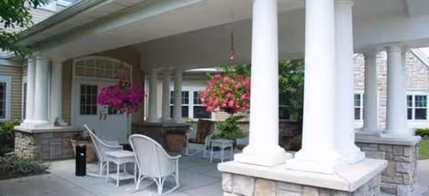 Front porch of Brookdale Pittsford with white columns, seating, and hanging flower baskets