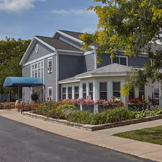Exterior view of Buckley Landing facility with blue siding, awning, and flower beds