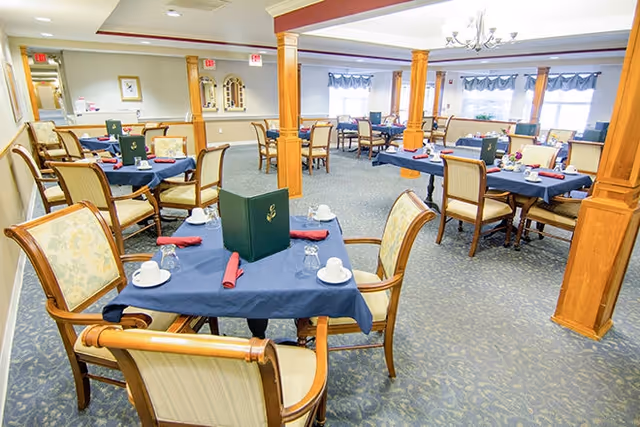 Dining room with several tables dressed in navy tablecloths, place settings, and wooden chairs around polished wood columns.