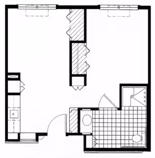 Black and white architectural floor plan of an assisted living unit showing a kitchen area, a bathroom with a shower, toilet, and sink, and an open living space with closets.