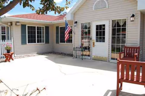 Outdoor patio area in front of a memory care facility with chairs and an American flag.