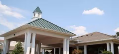 Entrance to The Pines at Greenville Assisted Living & Memory Care with a green metal roof.