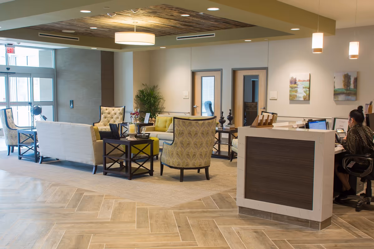 Bright reception lobby with a seating area of sofas and chairs and a front desk with a staff member working.