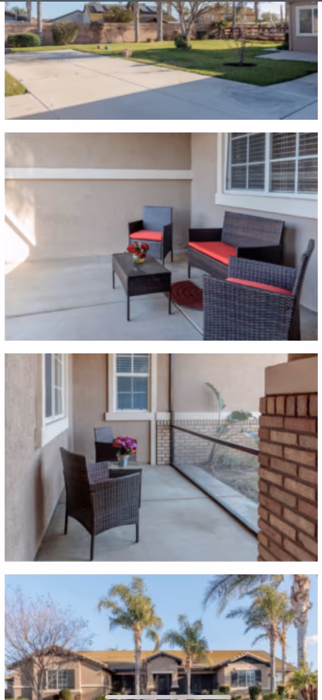 Covered front patio with wicker seating and red cushions and a view of the building exterior with palm trees.