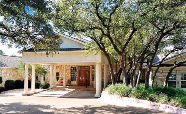 Front entrance of S.P.J.S.T. Assisted Living with columns and trees.