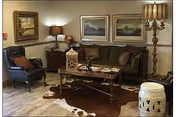 Cozy living room in a senior facility with sofa, chairs, coffee table, lamps, and framed art.