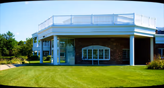 Facade of Hathaway Manor Extended Care with brick exterior, white columns, and a manicured lawn.