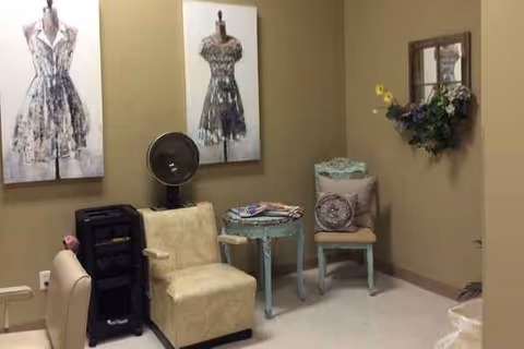A seating area inside a senior living facility with dress art prints, a fan, and decor.