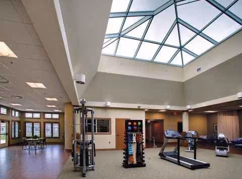 Spacious indoor fitness area featuring a glass skylight ceiling and exercise machines.