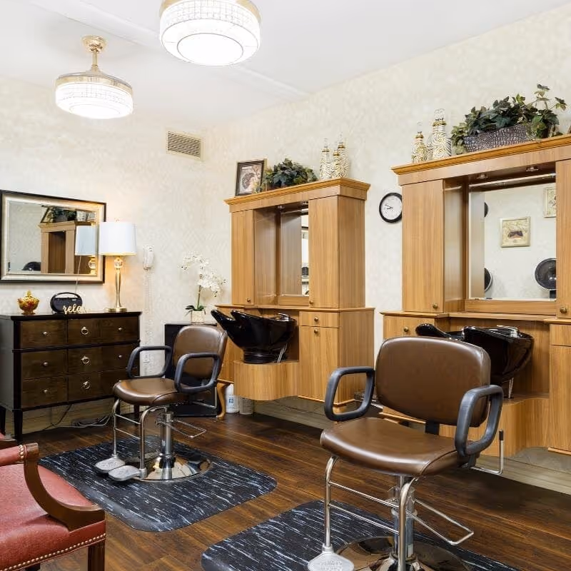 Interior salon area with styling chairs, washbasins, mirrors, and wooden cabinetry.