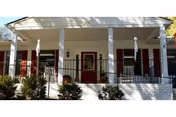 White front porch with columns, red shutters, and greenery on a Dutch Haven Assisted Living building.