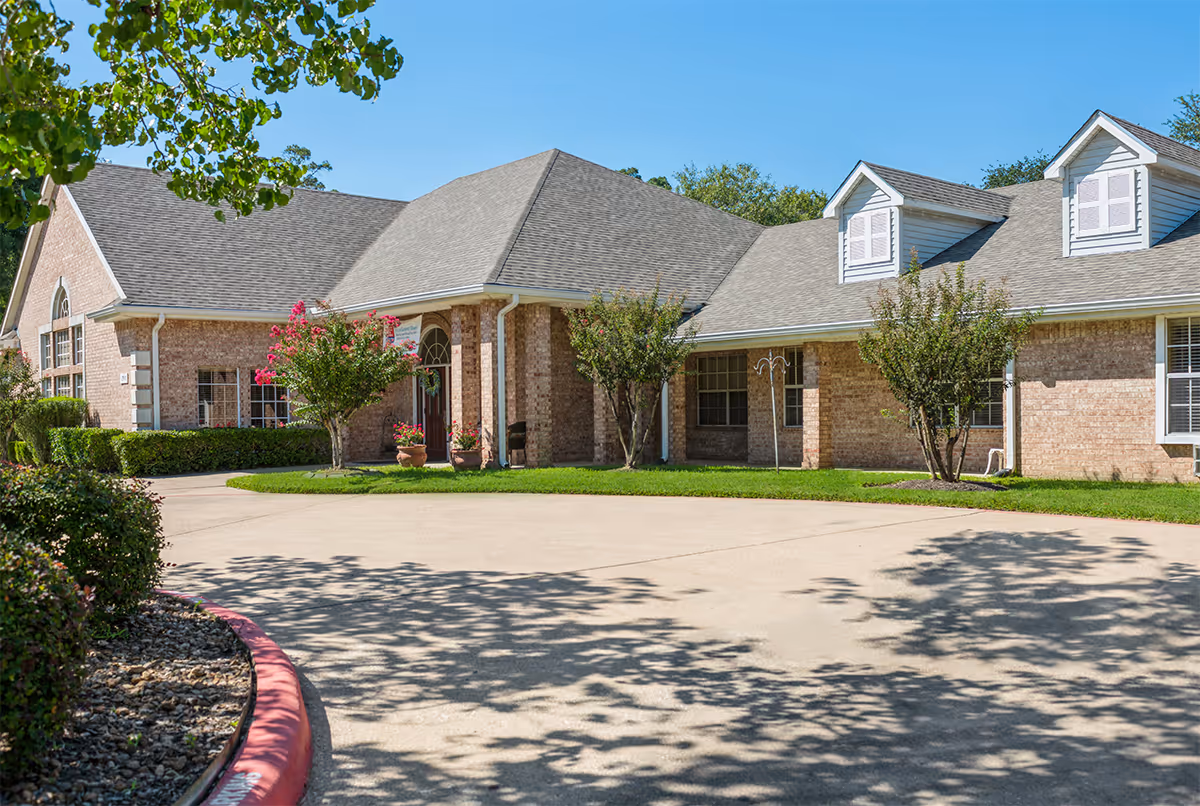 Brick senior living facility exterior with landscaped entrance and curved driveway.